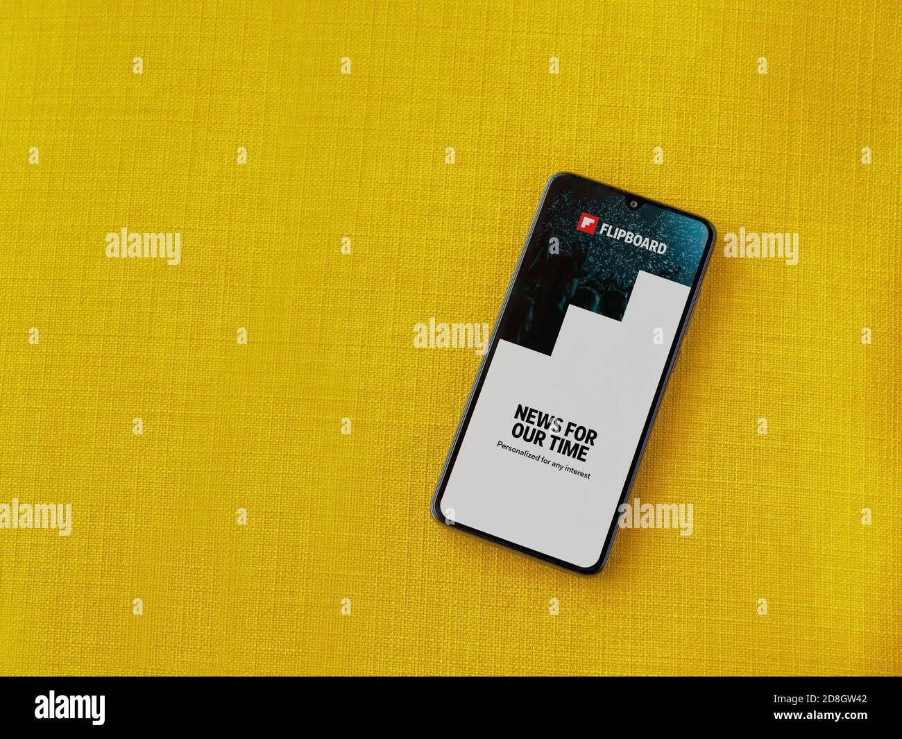 Lod, Israel - July 8, 2020: Flipboard app launch screen with logo on the display of a black mobile smartphone on a yellow fabric background. Top view Stock Photo