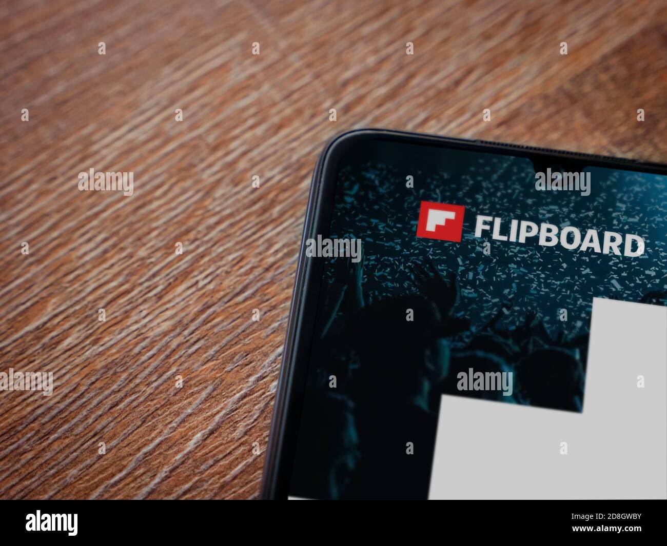 Lod, Israel - July 8, 2020: Flipboard app launch screen with logo on the display of a black mobile smartphone on wooden background. Top view flat lay Stock Photo