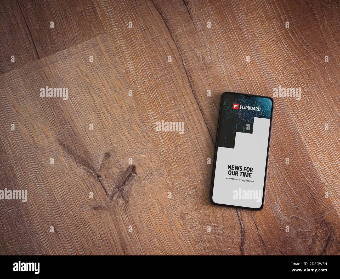 Lod, Israel - July 8, 2020: Flipboard app launch screen with logo on the display of a black mobile smartphone on wooden background. Top view flat lay Stock Photo