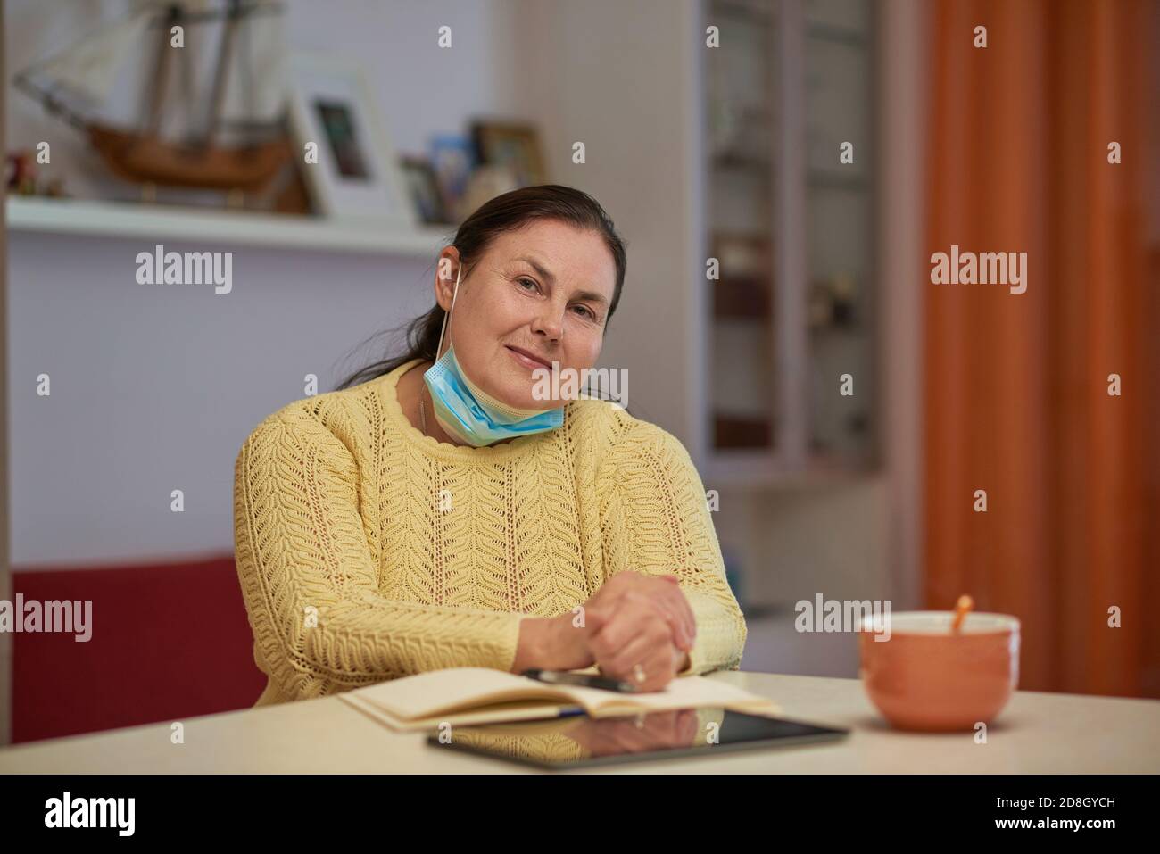Senior woman in yellow sweater looking in the camera with mask  Stock Photo