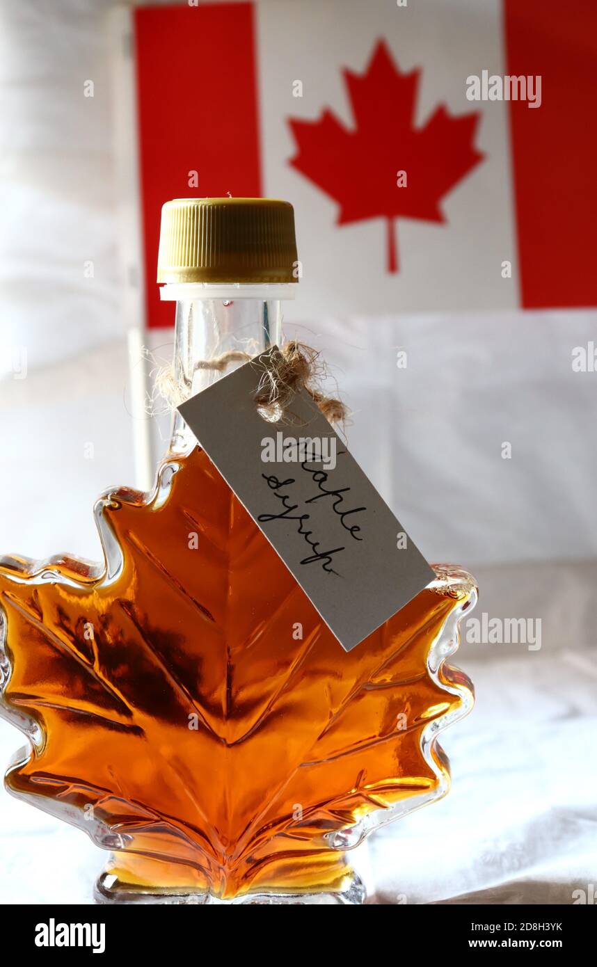 Maple syrup in a maple leaf shaped bottle, with handwritten tag and the flag of Canada in the