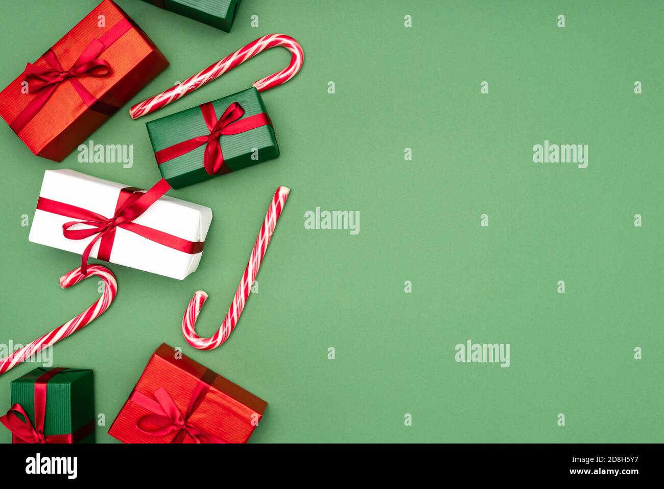top view of colorful gift boxes and candy canes on green background ...