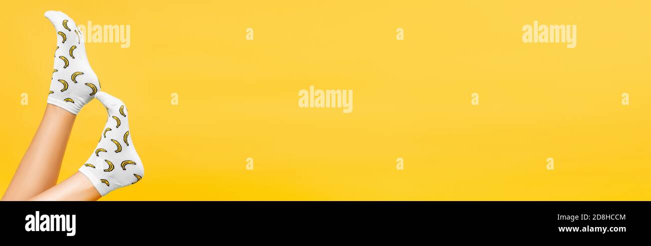 Female legs in socks with print isolated on yellow, banner Stock Photo