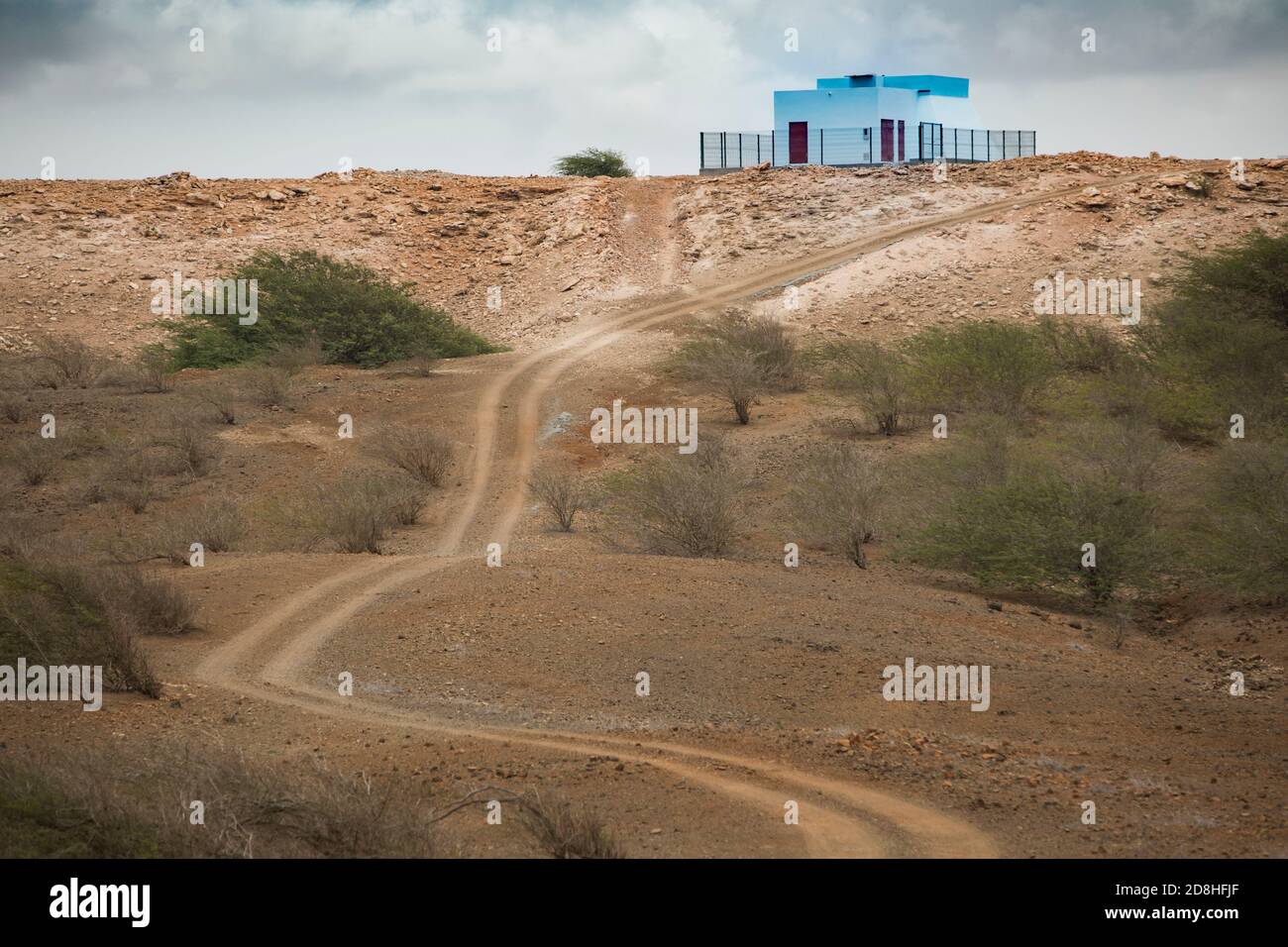 A bright blue painted water reservoir and pumping station can be seen atop a dry and barren hill on the island of Maio in Cape Verde. Stock Photo