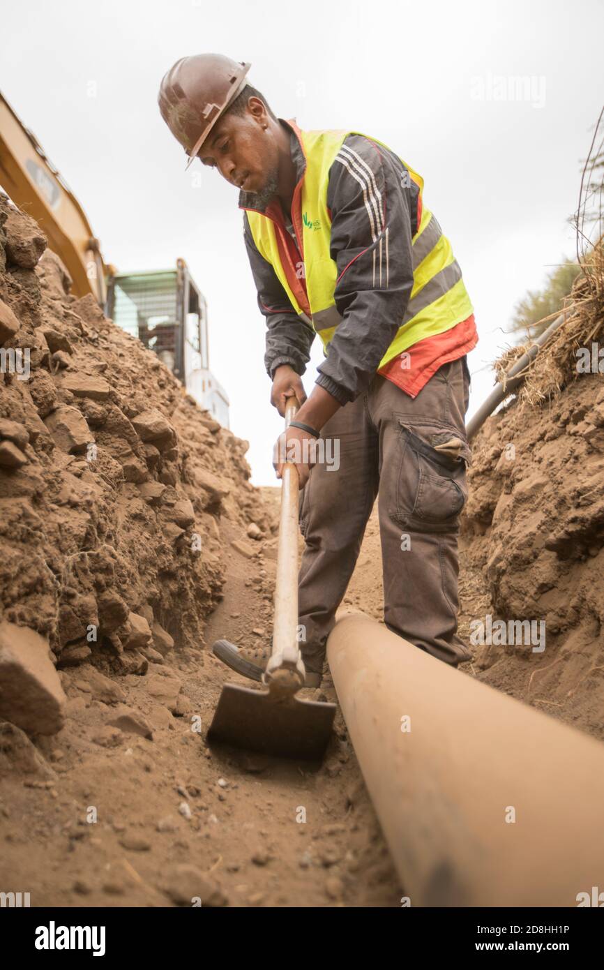 A construction worker works to install a new water line underground on