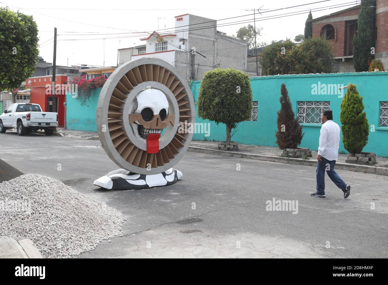 Non Exclusive: MEXICO CITY, MEXICO - OCTOBER 30: A person wears face mask while walks front a monumental skull made of cardboard,  were put to decorat Stock Photo