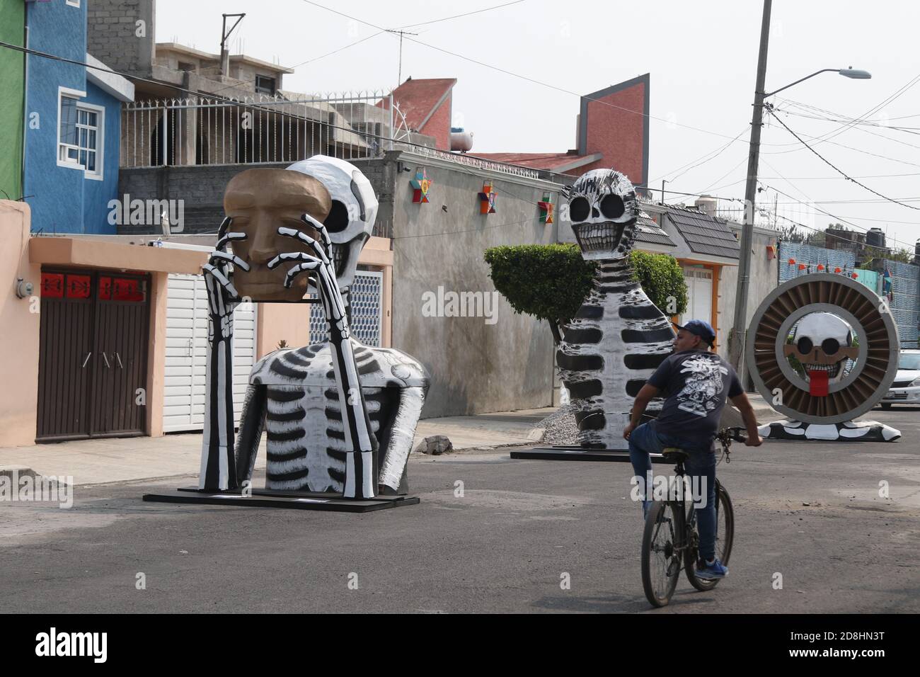 Non Exclusive: MEXICO CITY, MEXICO - OCTOBER 30: A person wears face mask while walks front a monumental skull made of cardboard,  were put to decorat Stock Photo