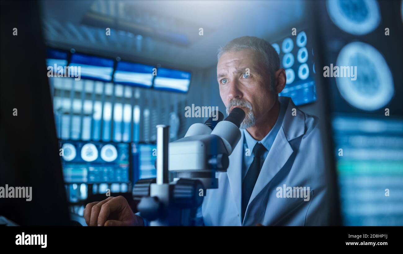 Senior Medical Research Scientist Looking under the Microscope in the Laboratory. Neurologist Solving Puzzles of the Mind and Brain. In the Laboratory Stock Photo