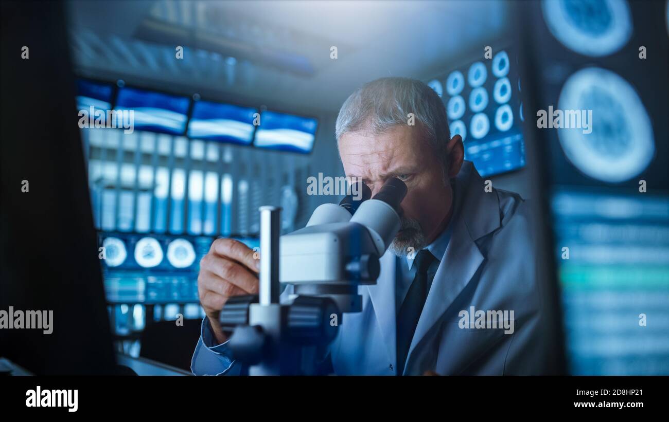Senior Medical Research Scientist Looking under the Microscope in the Laboratory. Neurologist Solving Puzzles of the Mind and Brain. In the Laboratory Stock Photo