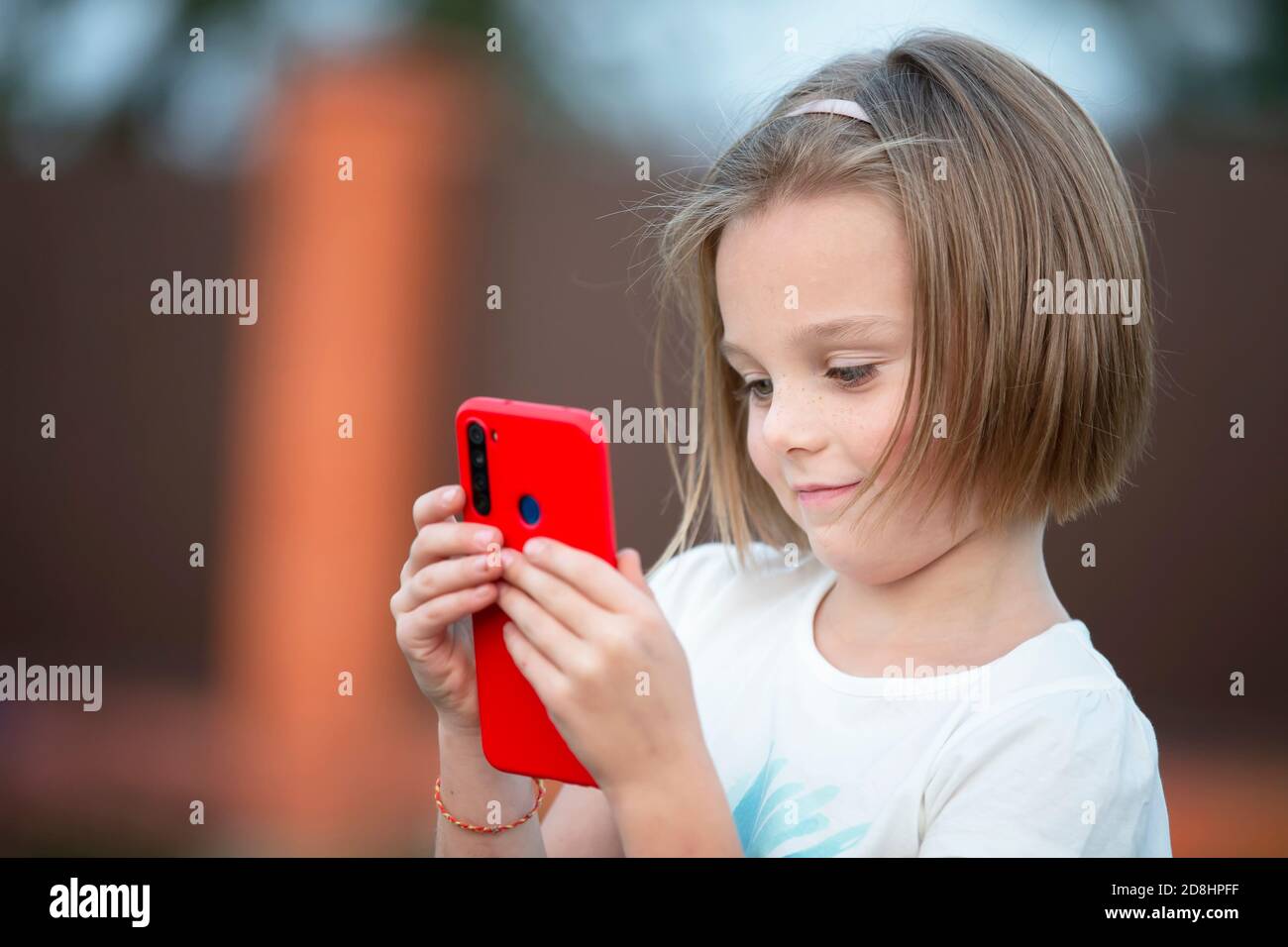 Child with a smartphone. The little girl is talking with a red phone