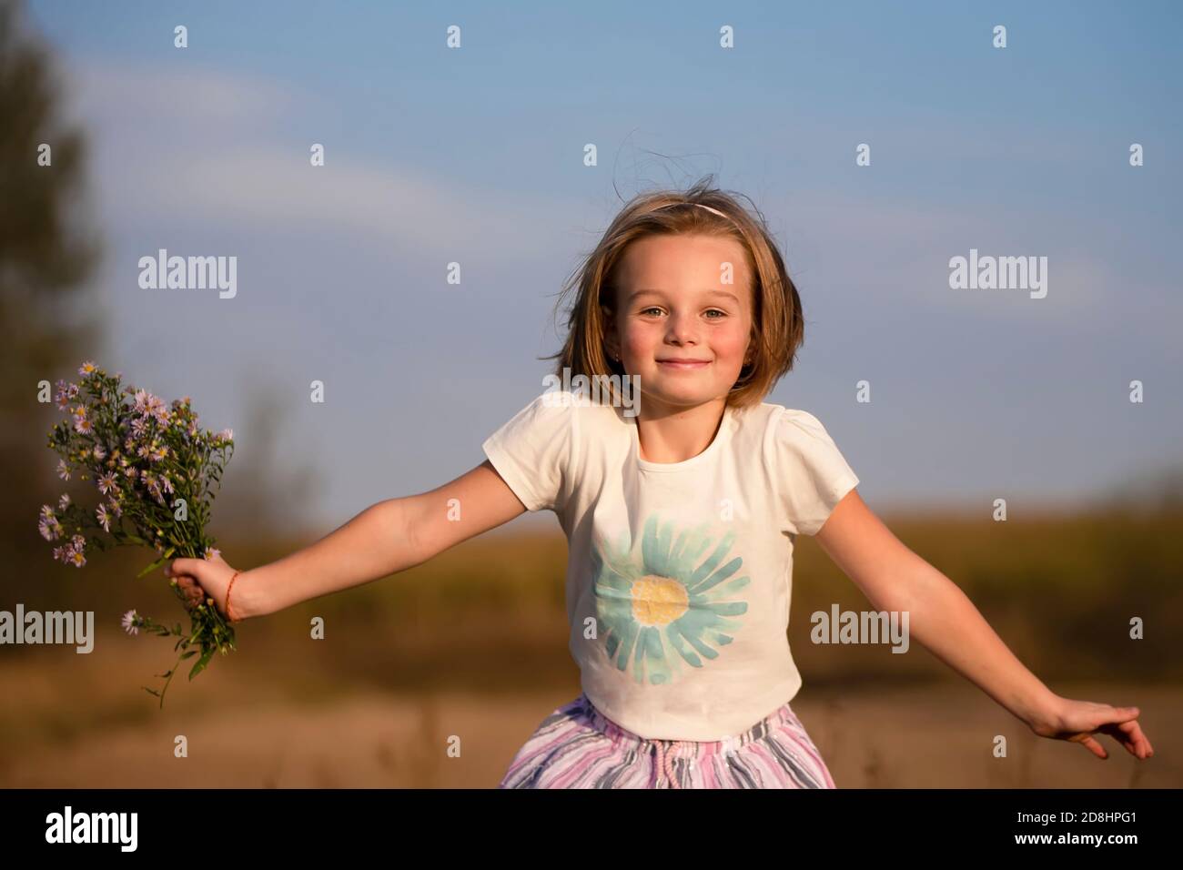 Happy little girl in the meadow with a bouquet of flowers. Child on a ...