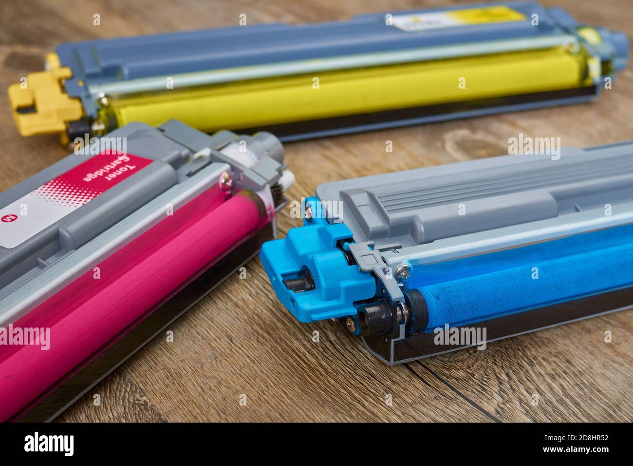 Three toner cartridges for color laser printer stacked on wooden table Stock Photo