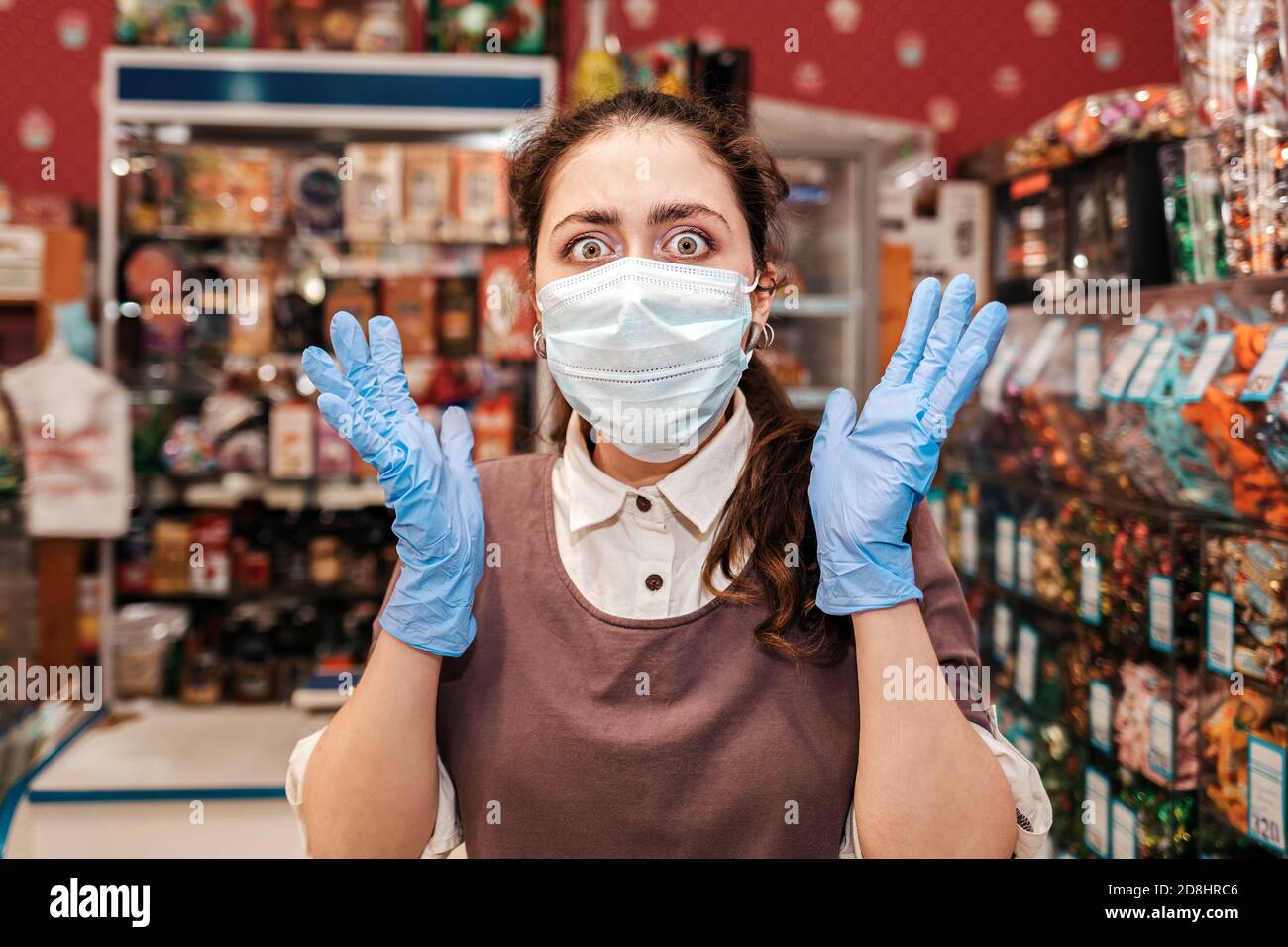 Portrait of woman in rubber gloves and a medical mask throws her hands ...