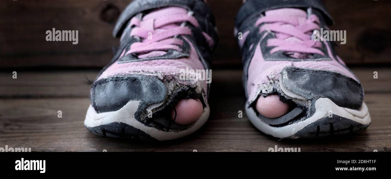 Worn out old shoes with holes in the toes used by homeless child Stock