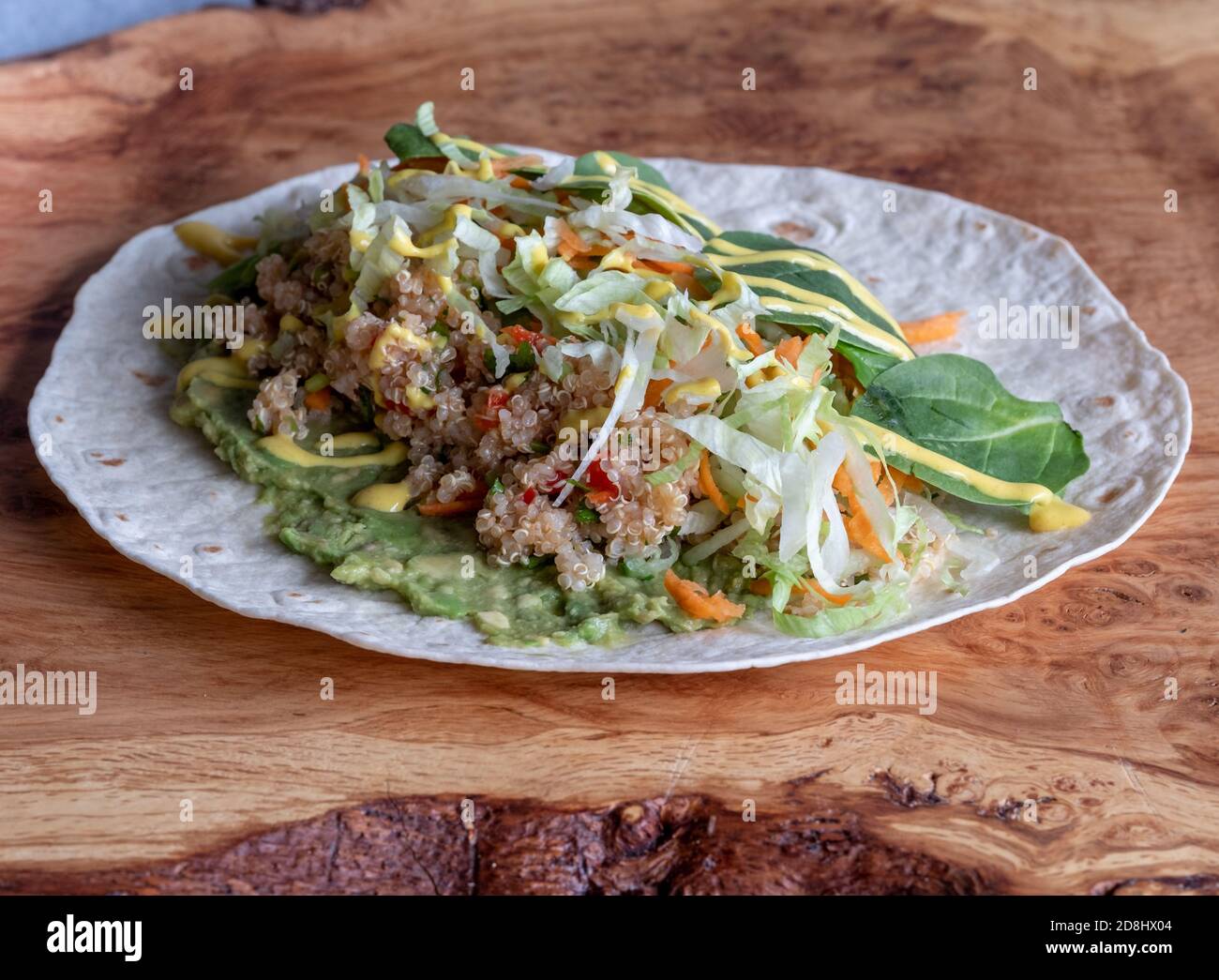 Open wrap with guacamole, quinoa, colourful salad and sauce over. Stock Photo