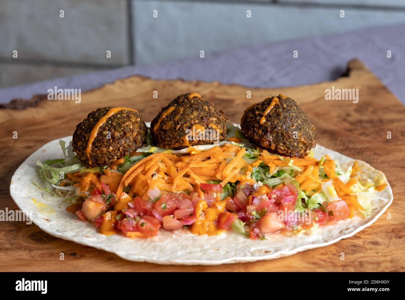 Fried falafal balls with colourful salad in a wrap, with sauce over. Stock Photo
