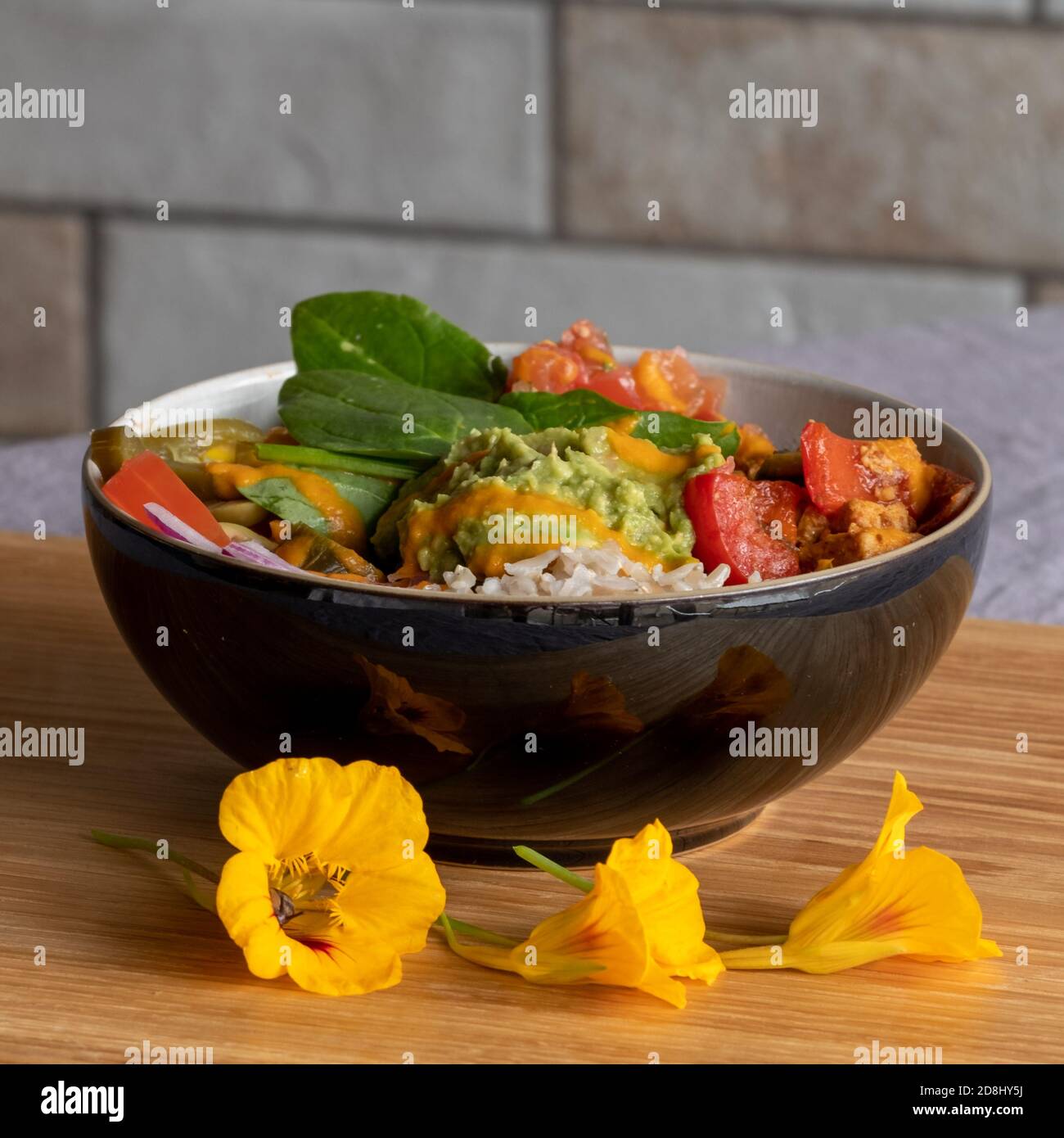Colourful vegan bowl food with avocado, tomato, spinach leaves. Vertical view. Stock Photo