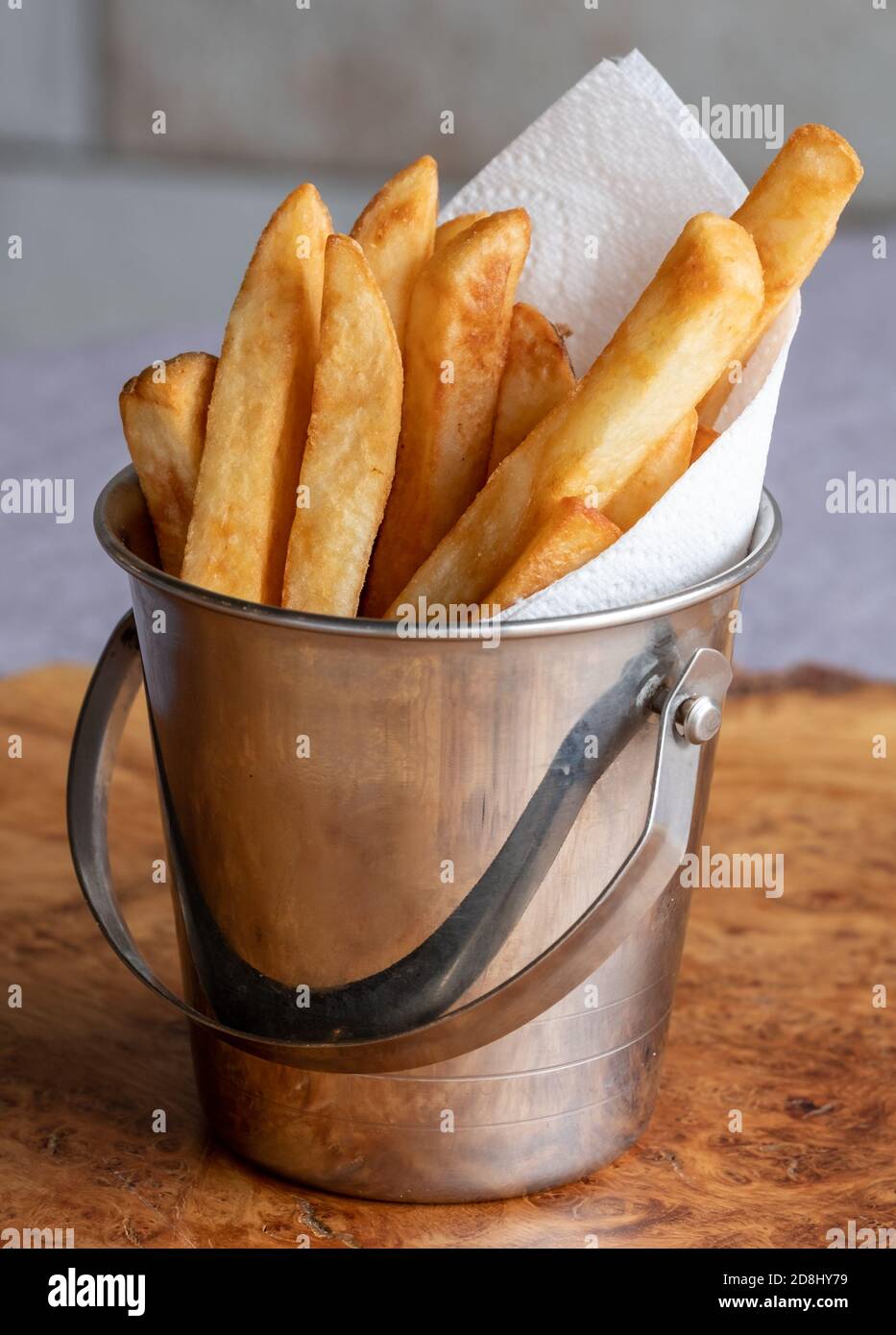 French fries served in a small metal bucket with napkin. Vertical view. Stock Photo