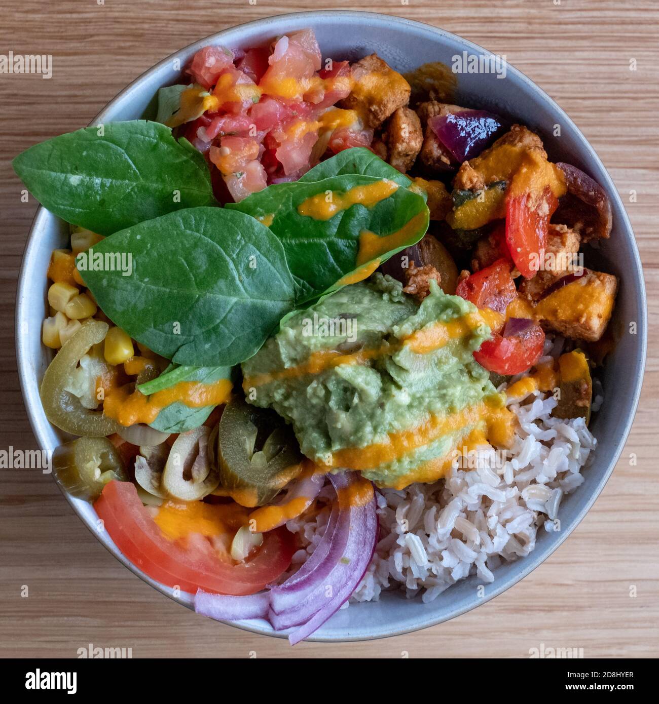 Colourful vegan bowl food with avocado, tomato, spinach leaves. Photographed from above. Stock Photo