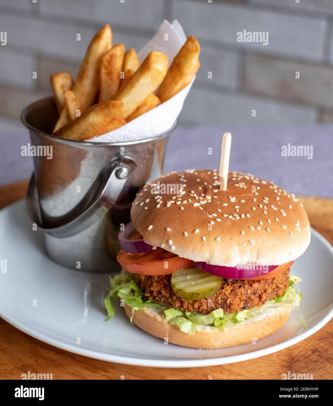 Vegan veggie soya burger in bun with salad and relish, and chips on the side. Stock Photo