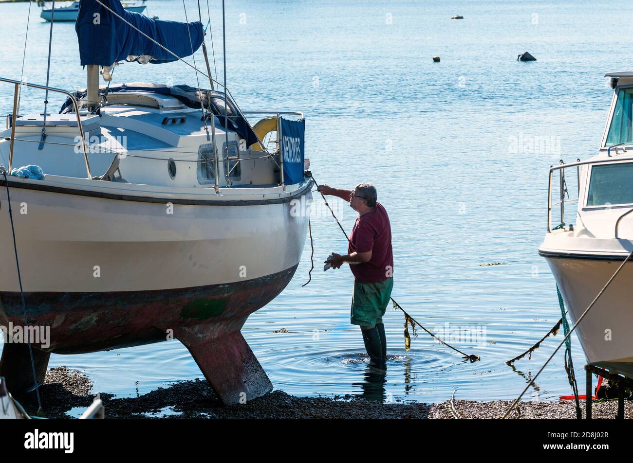 Yachtsman painting hull of Westerly twin keel sailing boat beside the