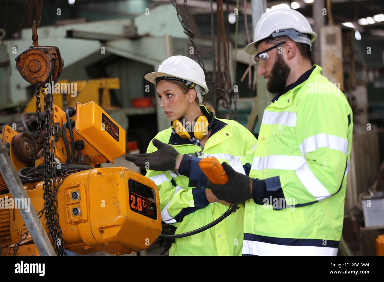 Men and female workers in factory operating machine in workshop floor ...