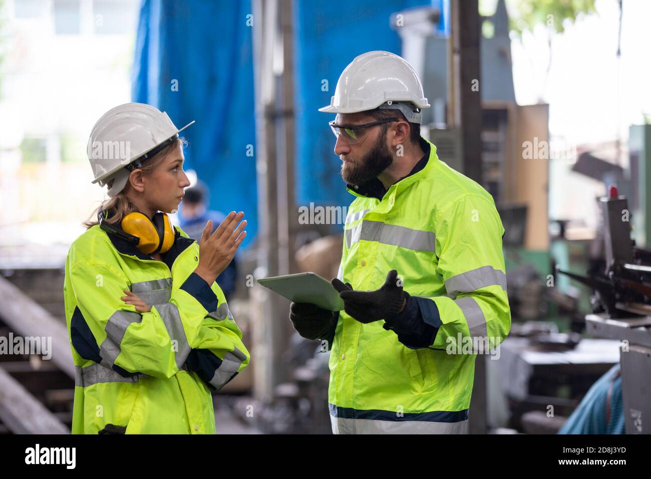 Men and female workers in factory operating machine in workshop floor. Stock Photo