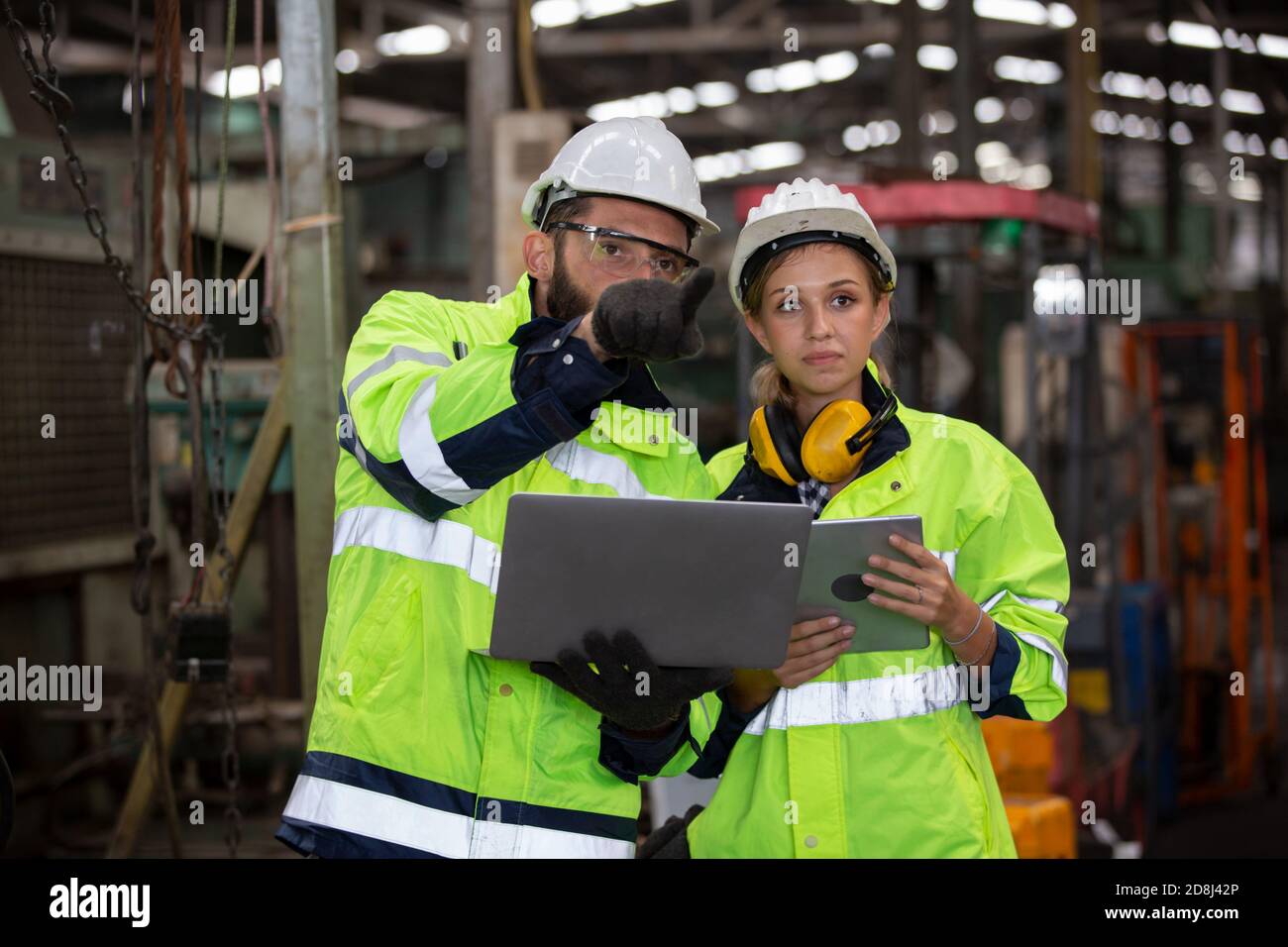 Men and female workers in factory operating machine in workshop floor. Stock Photo