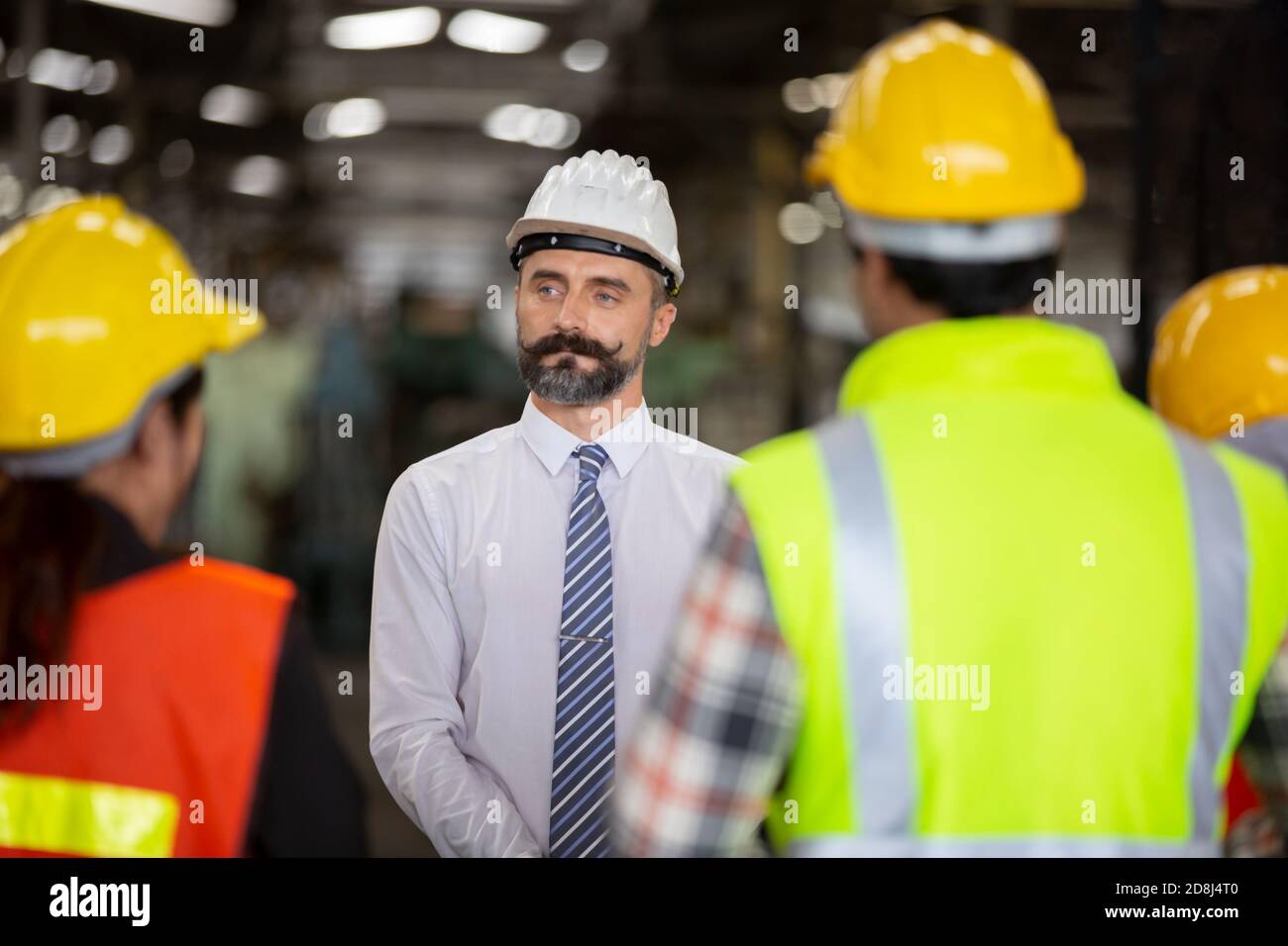 Male Industrial Engineers Talk with Factory Worker . They Work at the Heavy Industry Manufacturing Facility. Stock Photo