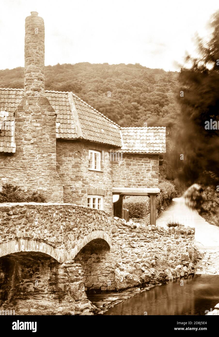 Sepia toned photograph taken on a paper negative in a 7 x 5 inch plate camera in July 2020 of the house beside the medieval packhorse bridge on Exmoor Stock Photo