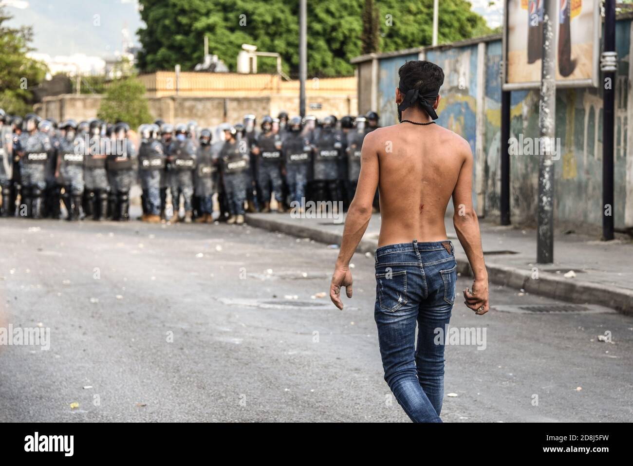 Beirut, Lebanon, 30 October 2020. Approaching the police line with a stone to throw as a small group of men from Tripoli and Beirut clash with Lebanese Interior Security Forces. SCuffles broke out during an attempt by pan-islamic group Hizb Ut Tahrir to march to the French Embassy in protest of what they view as president Emmanuel Macron's anti-islamic stance. Emotions ran high as it was felt the Prophet Mohammed is being disrespected during his birthday month. Credit: Elizabeth Fitt/Alamy Live News Stock Photo