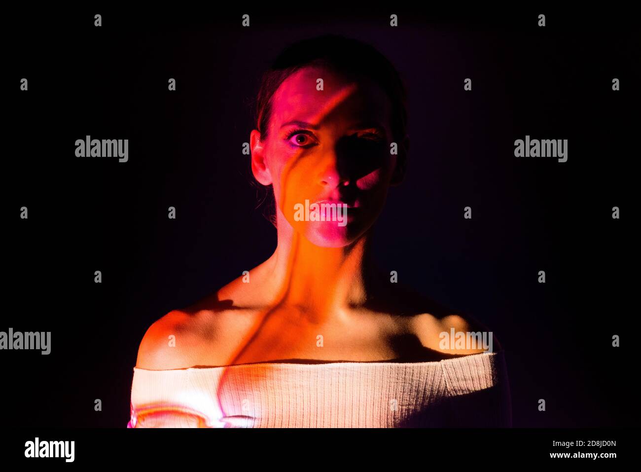 Creative portrait of a woman illuminated with colored lights on dark ...