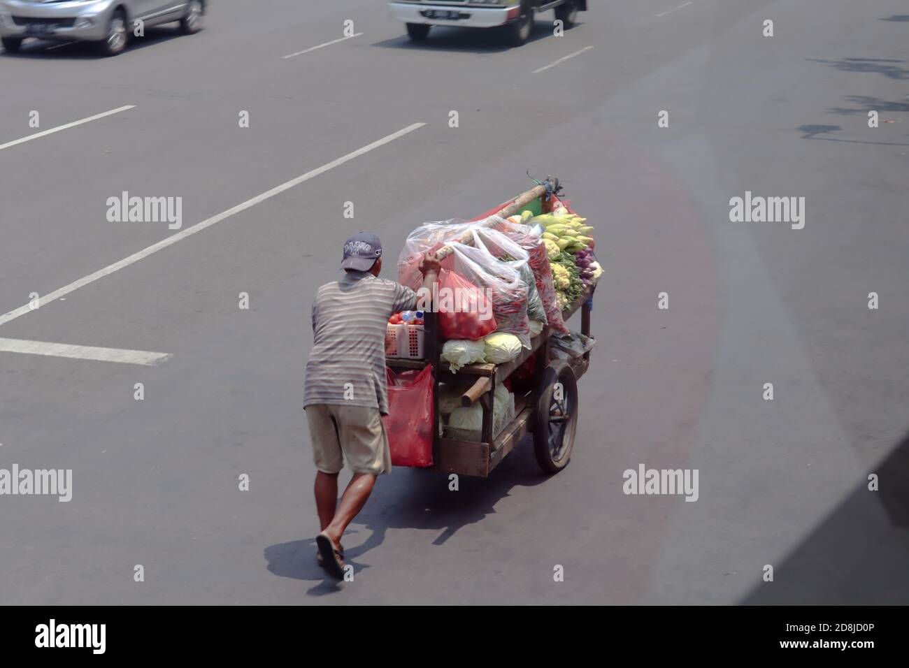 jakarta / Indonesia - September 23, 2020. A mobile vegetable trader pushing his cart during the day Stock Photo