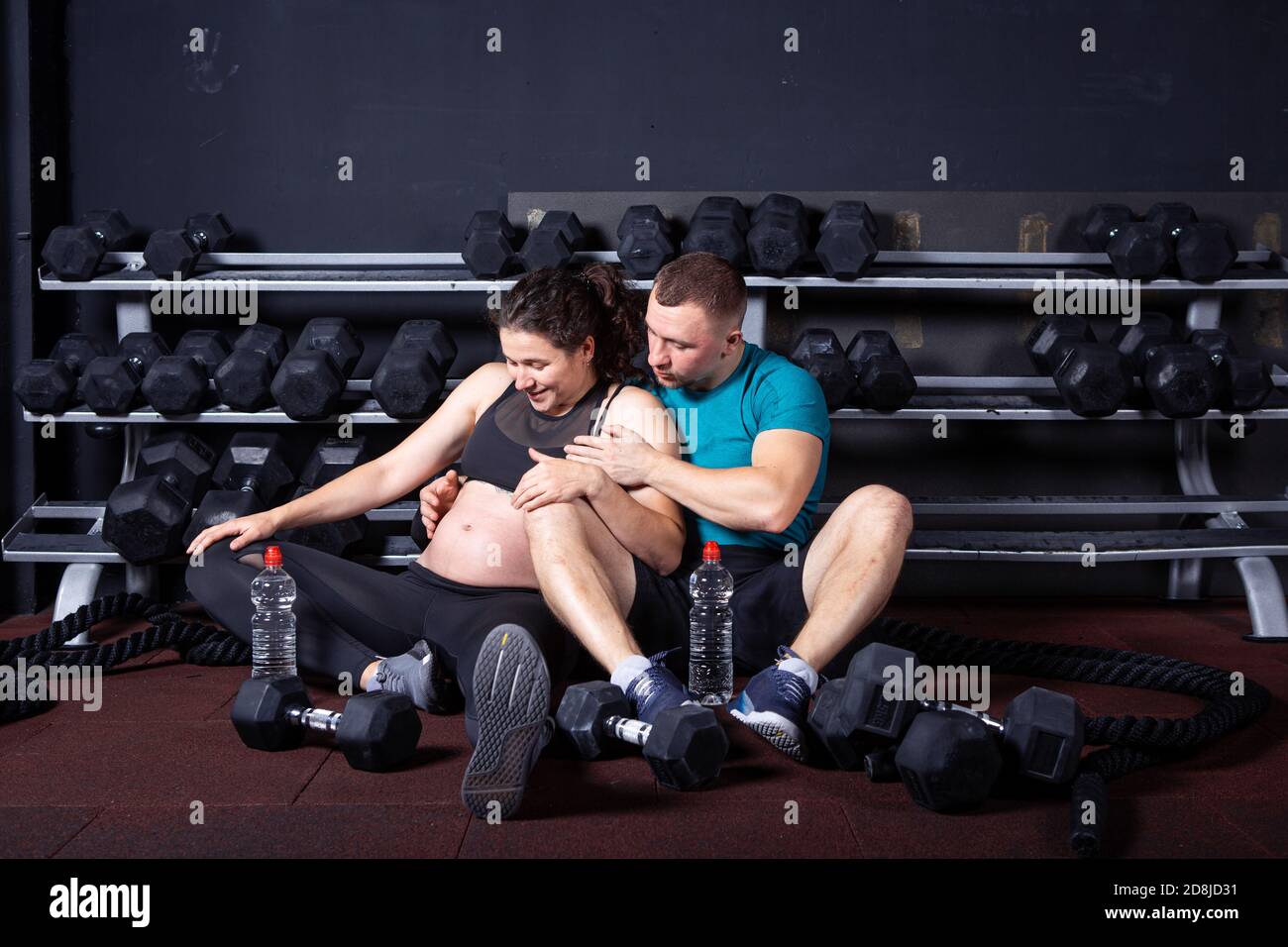 Pregnant woman goes for sports with her husband in gym for cross