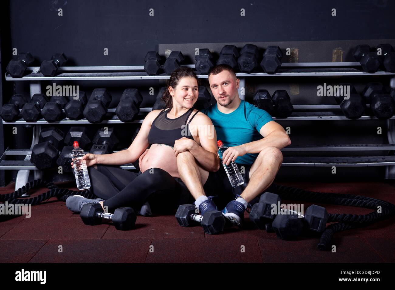 Pregnant woman goes for sports with her husband in gym for cross