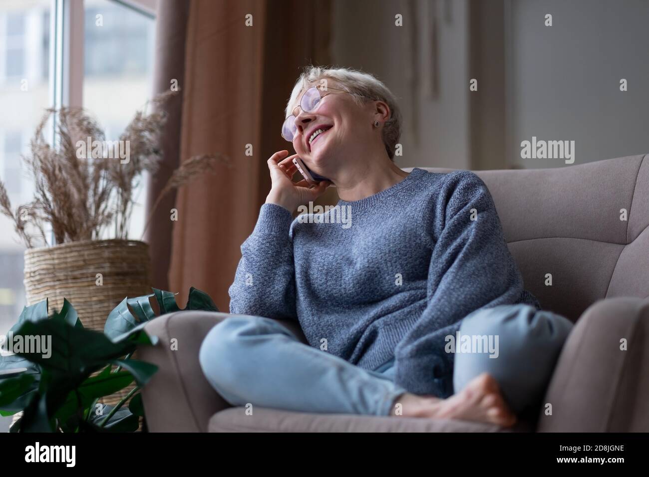 Senior woman talking on mobile phone at home Stock Photo
