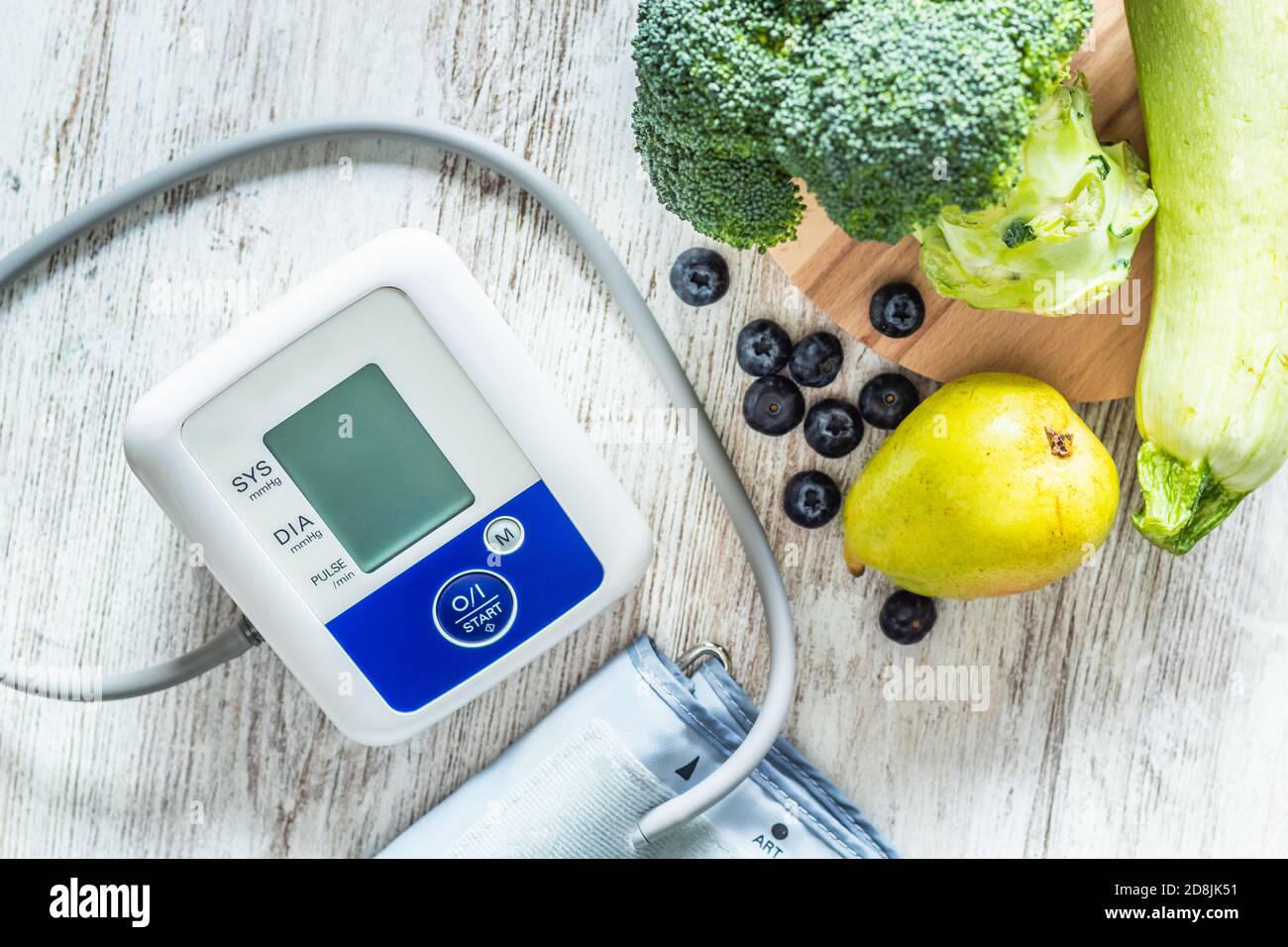 Blood pressure monitor on a table next to table of green fruits and