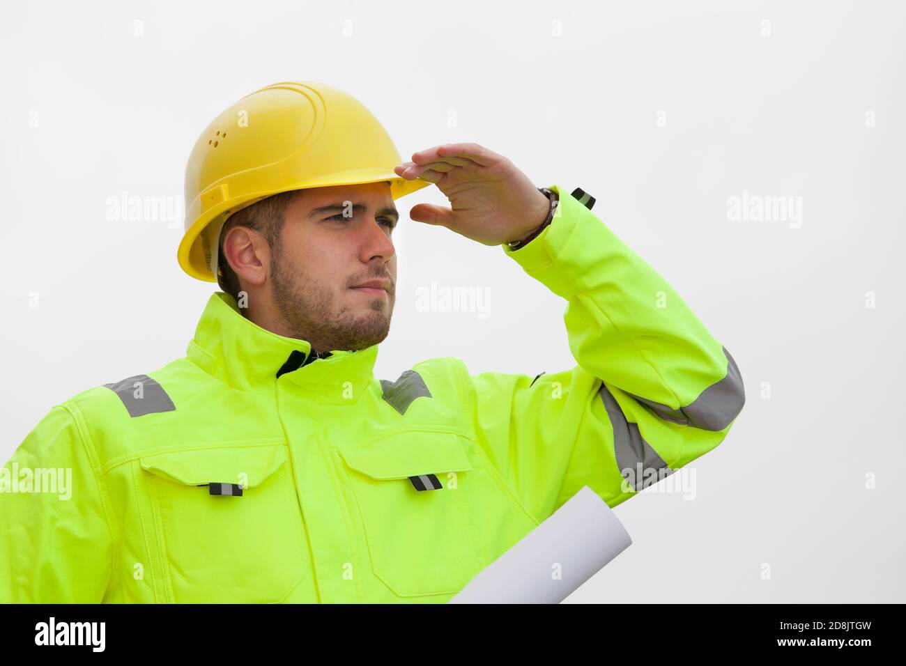 Young engineer or architect in green protective clothing looking out for a sustainable future in front of bright sky Stock Photo