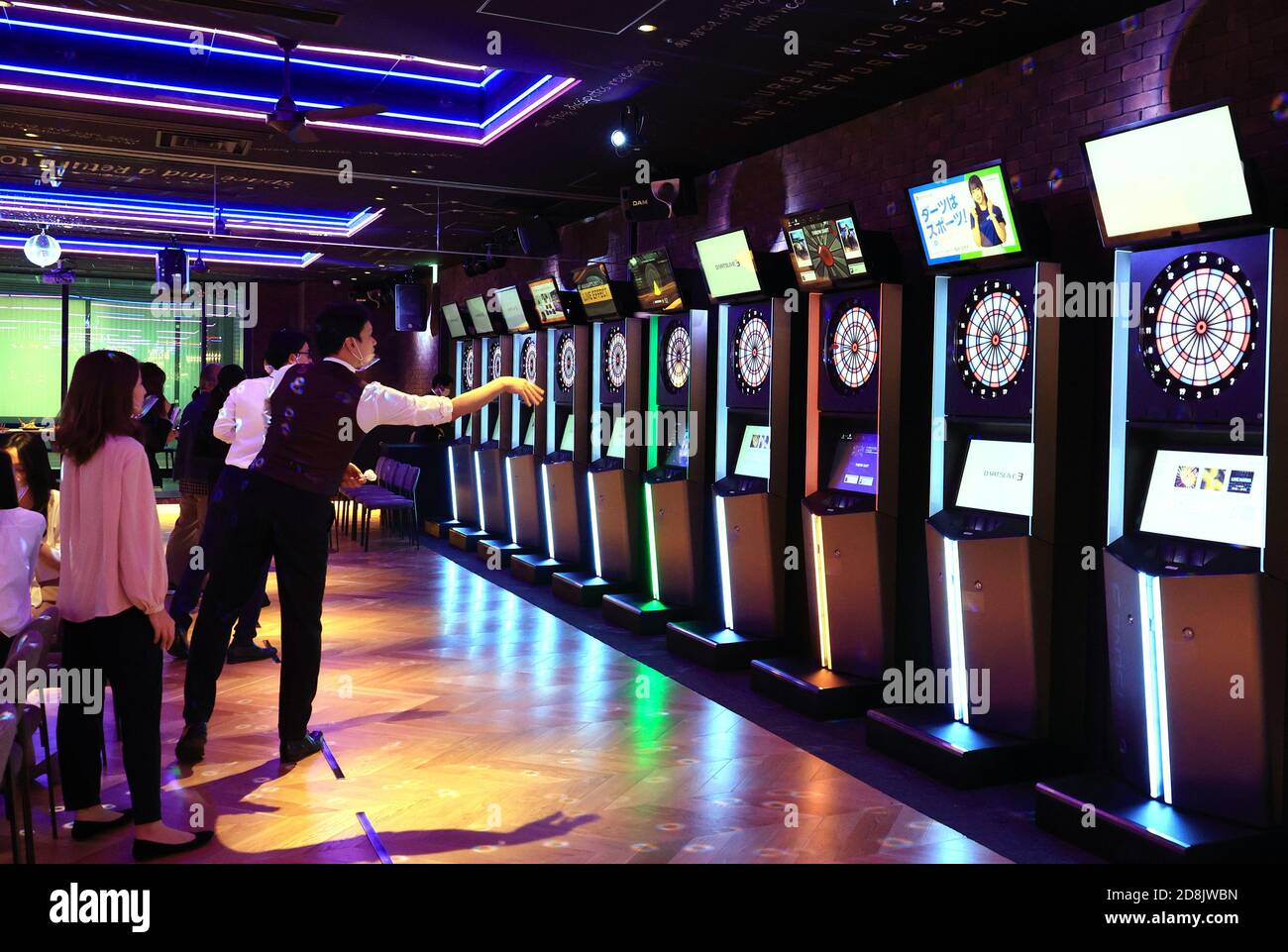 Tokyo, Japan. 30th Oct, 2020. Models play darts at a dinning bar of the  "Marunouchi Base" run by Japan's karaoke giant Daiichikosho at a press  preview of the new commercial institution "Marunouchi