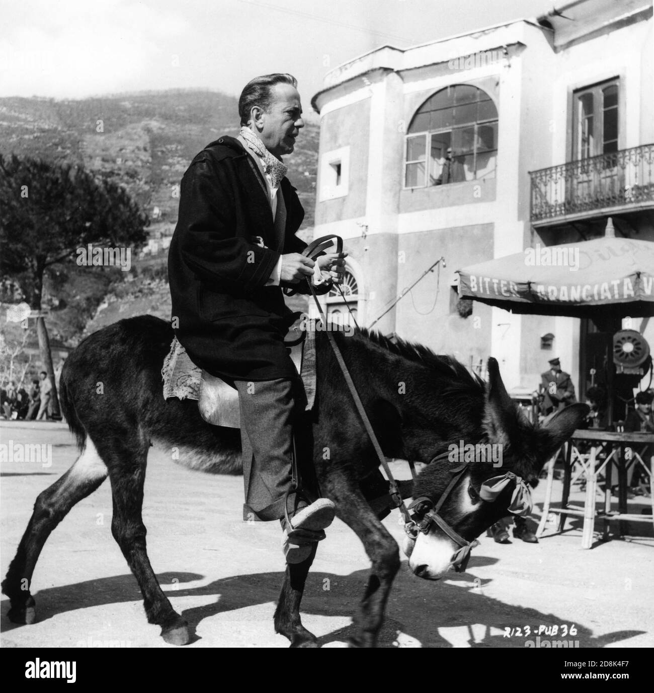 HUMPHREY BOGART riding Francisco the Donkey on set location candid in Ravello in Italy filming BEAT THE DEVIL 1953 director JOHN HUSTON novel Claud Cockburn screenplay Truman Capote and John Huston UK - Italy - USA co-production Romulus Films / Dear Film / Santana Pictures Corporation Stock Photo