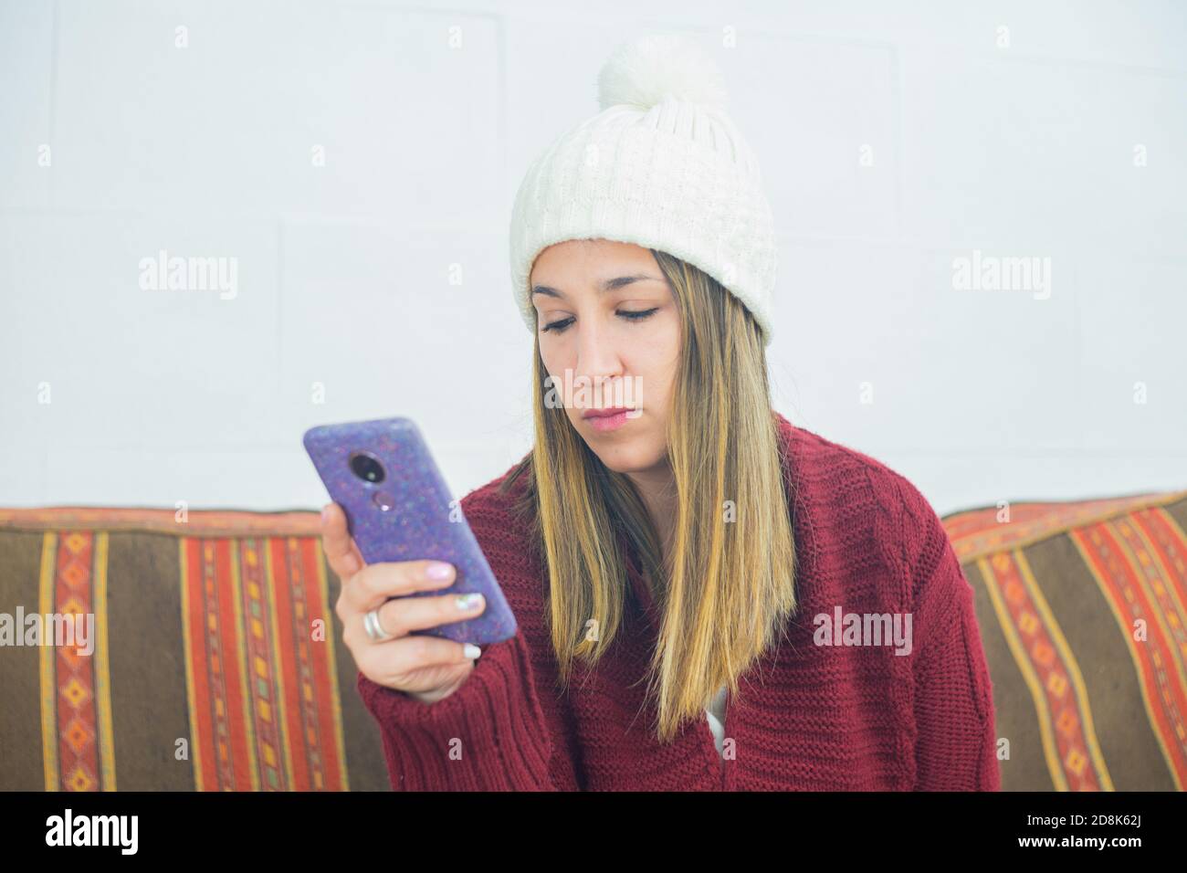 Closeup shot of a girl wearing a red cardigan looking at her phone Stock Photo