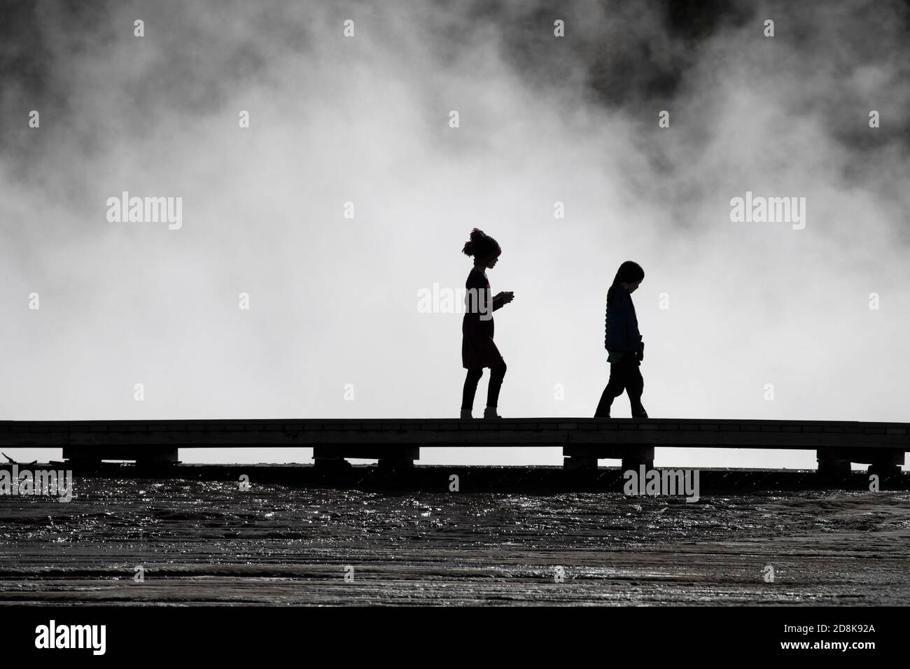 Yellowstone National Park tourists family children silhouette on boardwalk over geyser pools Stock Photo