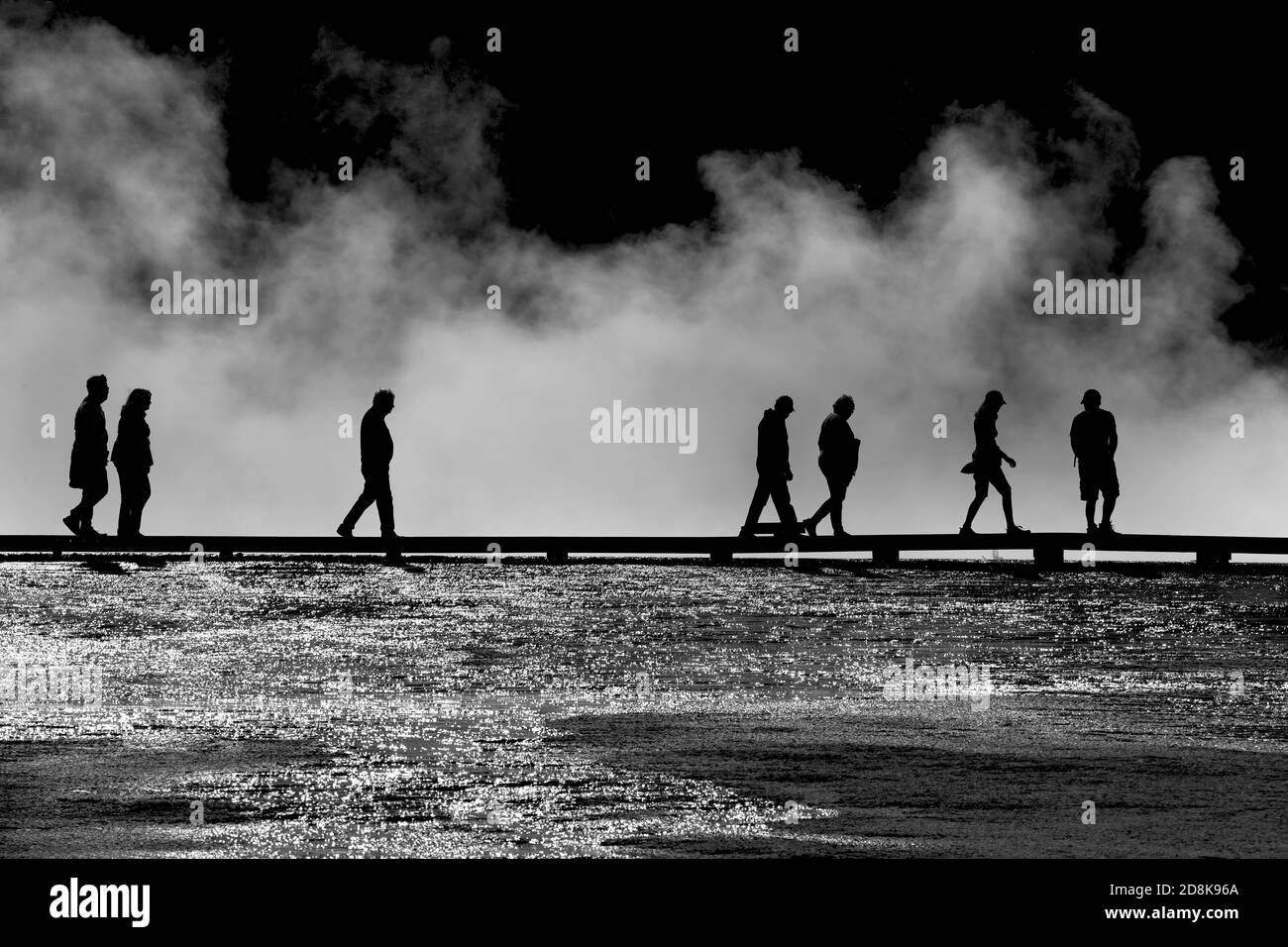 Yellowstone tourists silhouette on boardwalk over geyser pools Stock Photo