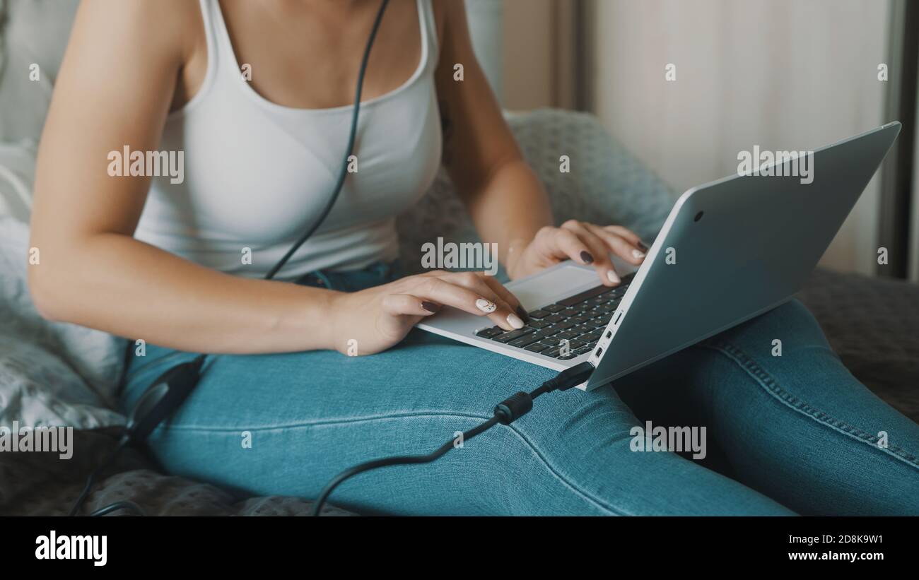 Young woman using laptop in her bedroom. Freelancer working from the comfort of her home. High quality photo Stock Photo