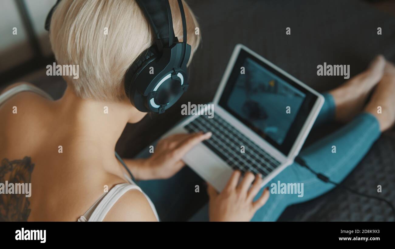 Young woman using laptop in her bedroom. Freelancer working from the comfort of her home. High quality photo Stock Photo