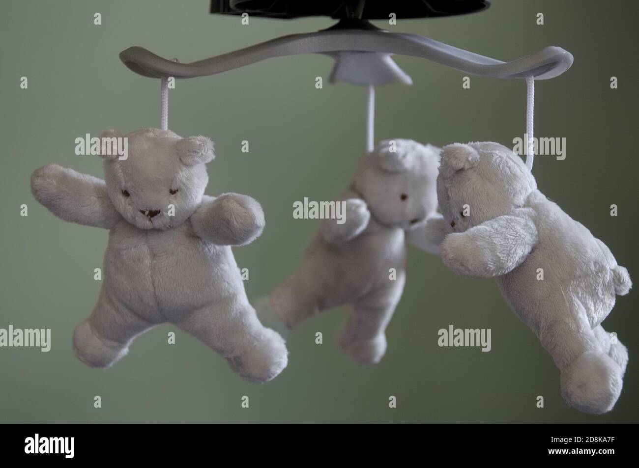 Three plush grey, white teddy bears hanging from a baby mobile, focus