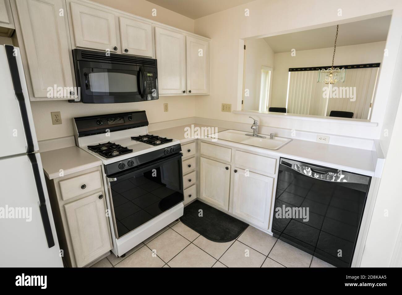 Clean 1990s suburban style condo kitchen with light colored cabinets and tile floor. Stock Photo