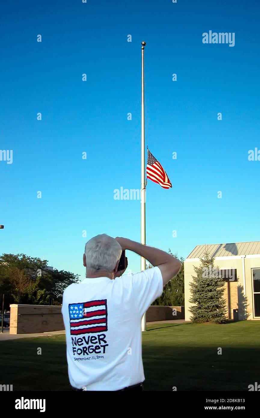 Male photographs flag at half mast - shirt reads ''remember 9/11''  september 11, 2001 Stock Photo