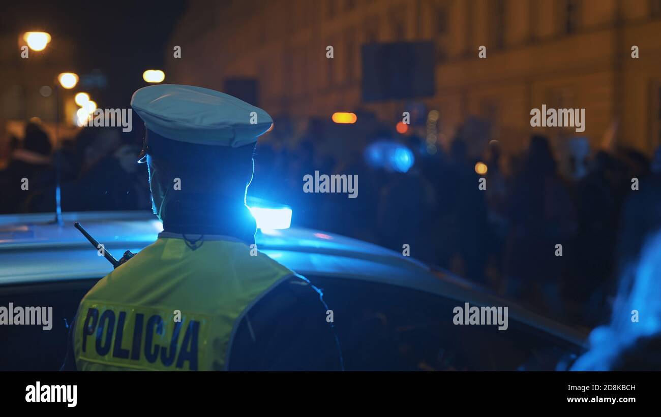 Warsaw, Poland 30.10.2020 - Anti abortion and human rights protest, Womens strike, demonstrants passing near police car illuminated by emergency light. High quality photo Stock Photo