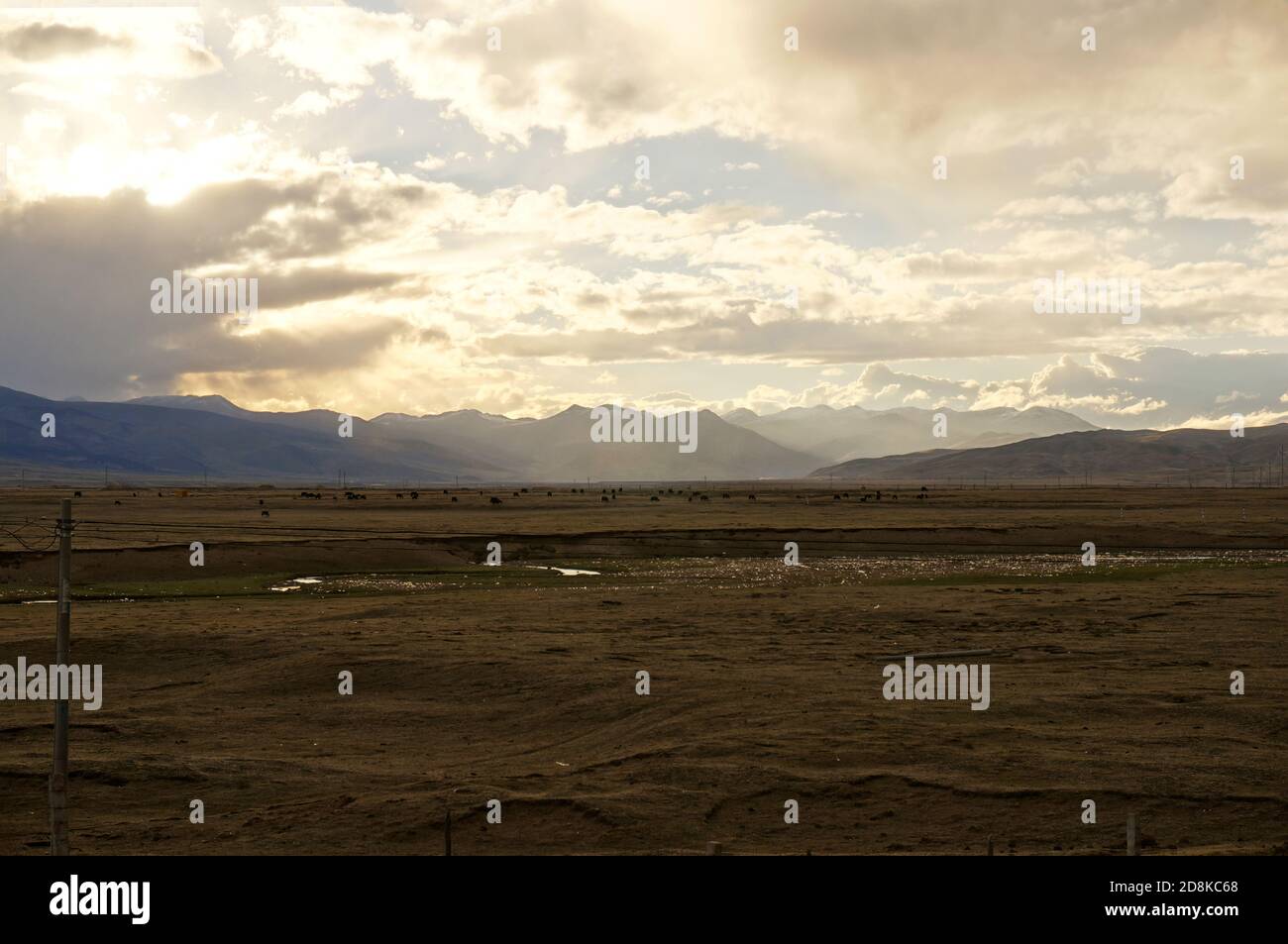 Sunset behind cumulus clouds over the brown steppe Stock Photo